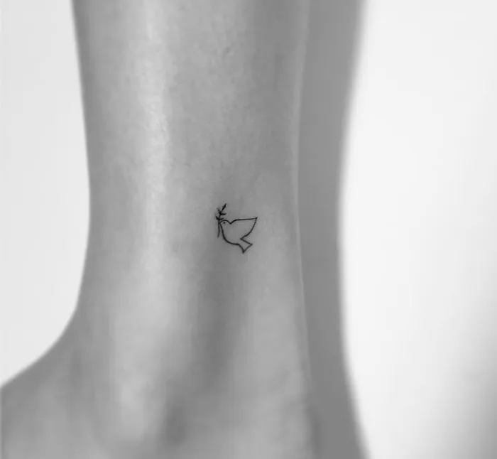 Minimalist tattoo of a small bird on an ankle, designed by a Korean artist.
