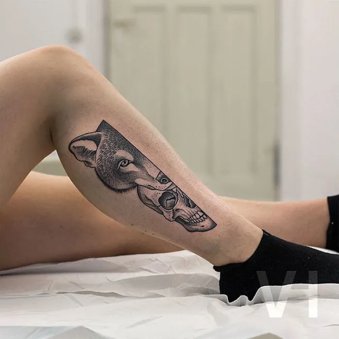 Symmetrical tattoo by Valentin Hirsch featuring a wolf and skull on a person's leg, blending nature and geometry.