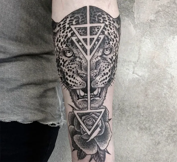 Symmetrical tattoo on arm featuring a leopard face and geometric patterns, blending nature with geometry.