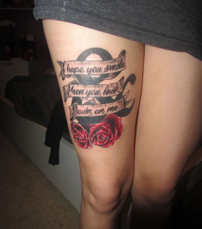 Tattoo with roses and script covering a leg scar, symbolizing a personal story.