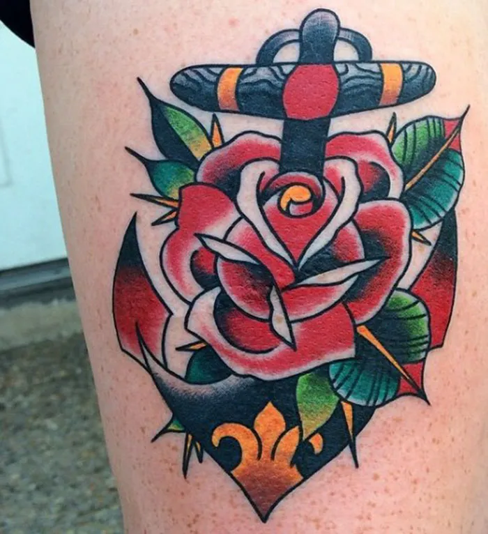 Colorful scar-covering tattoo featuring a rose and anchor design with vivid green leaves on a person's leg.