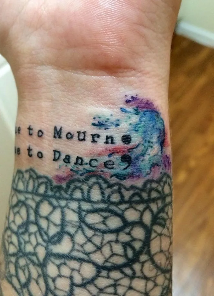 Scar-covering tattoo with colorful waves and text on a wrist.