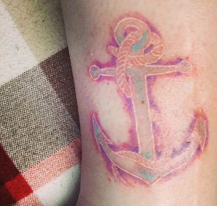 Anchor tattoo covering a scar with subtle purple and blue hues.