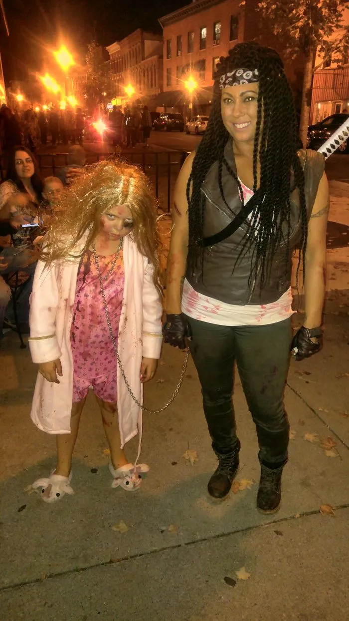 A woman and child in apocalyptic survivor outfits showing creative Halloween costume ideas on a night street