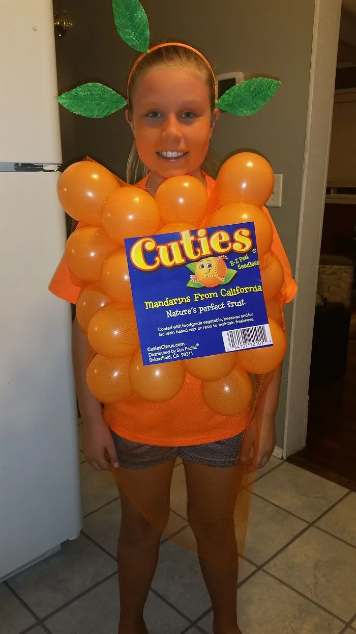 A girl wearing an orange Cuties mandarin bag creative Halloween costume made with balloons