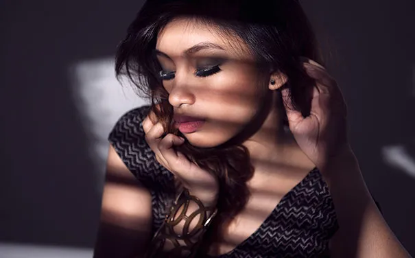 Woman in striped shadow lighting, illustrating photography tricks and illusions.