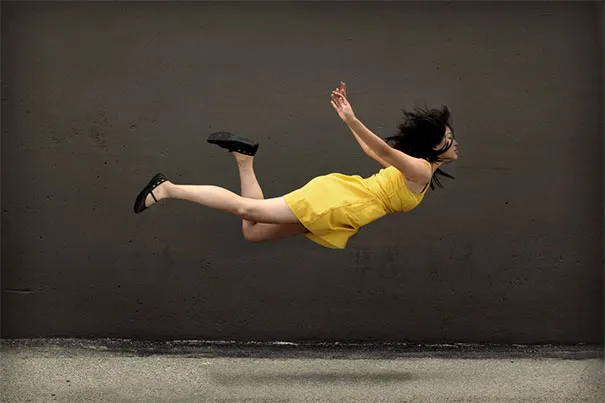 Woman in yellow dress seemingly floating against a dark wall, illustrating photography illusions.