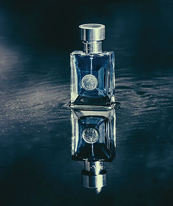 Perfume bottle on reflective surface, illustrating photography illusions.