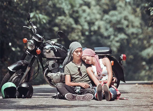 A couple sitting on a road with a motorcycle, showcasing the deceptive aspects of photography.