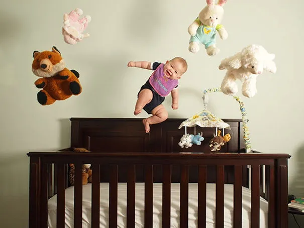 Baby floating with toys above crib, illustrating creative photography trick.