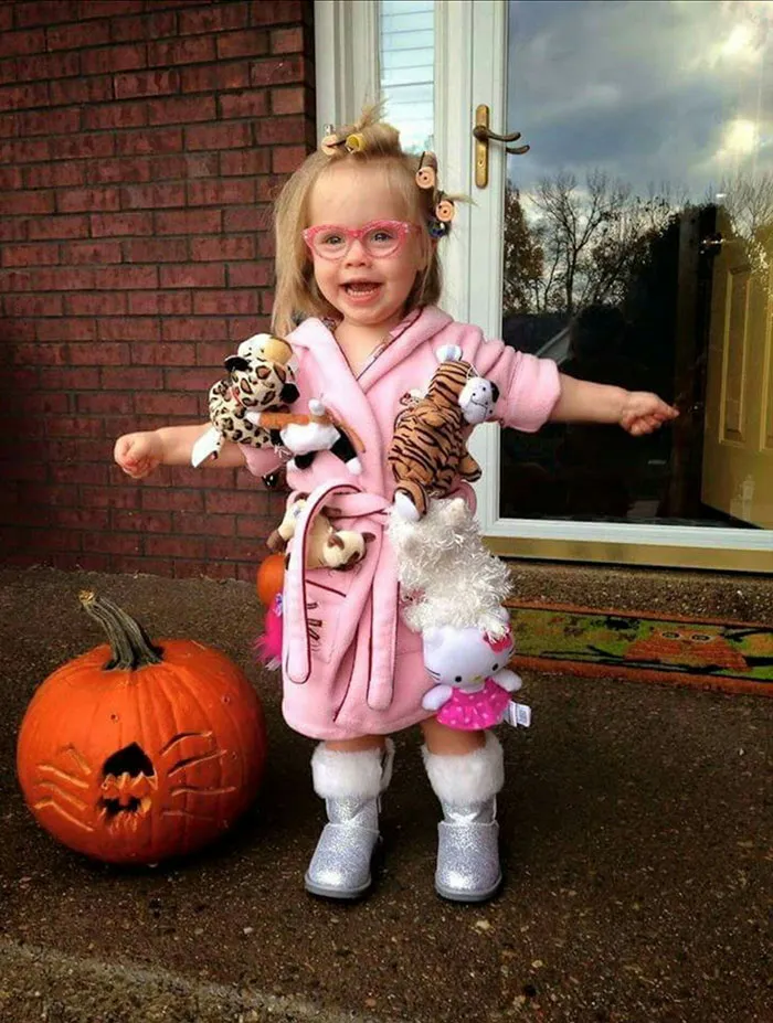Toddler girl dressed up in a pink bathrobe covered in stuffed animals as creative Halloween costume ideas