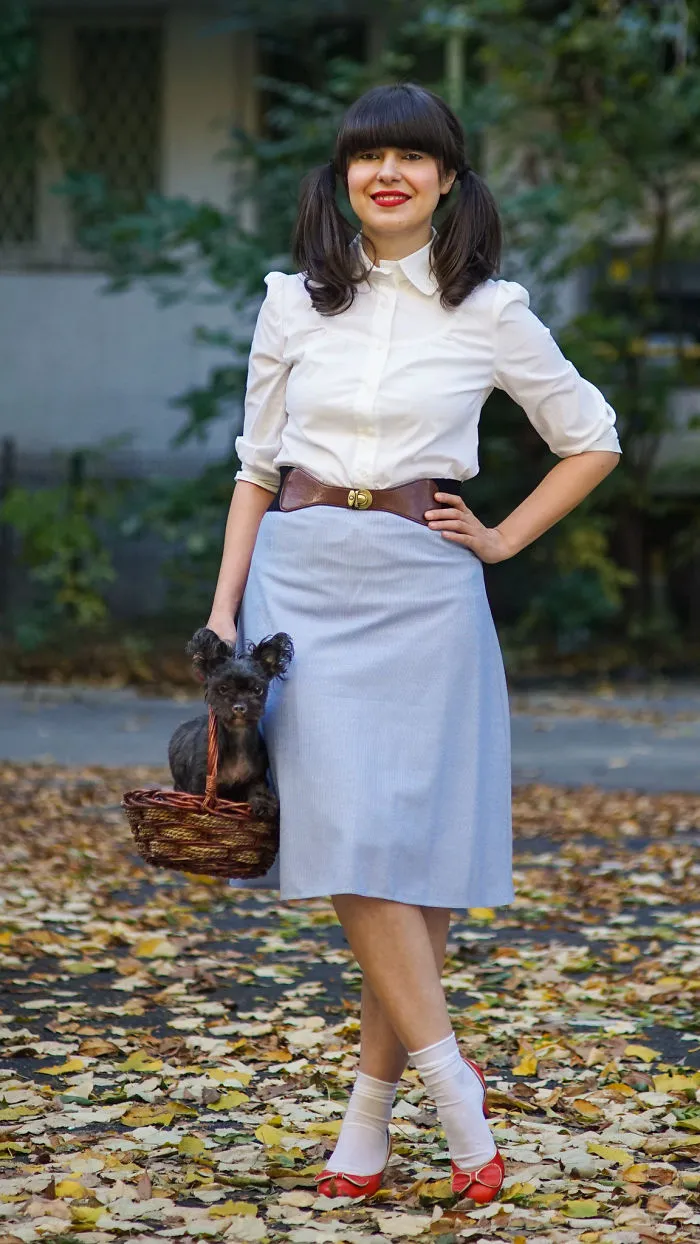 A woman dressed as Dorothy with a small dog in a basket for creative Halloween costume ideas.