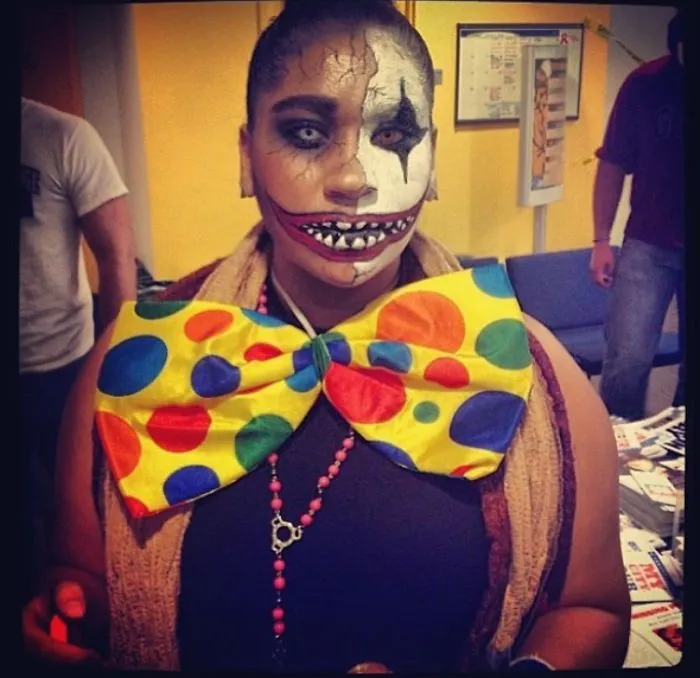 A person with creepy clown face paint and a giant polka dot bow tie as a creative Halloween costume idea.