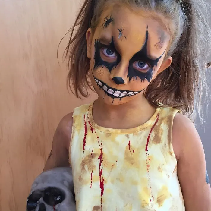 A young girl with creepy face paint and pigtails showing creative Halloween costume ideas