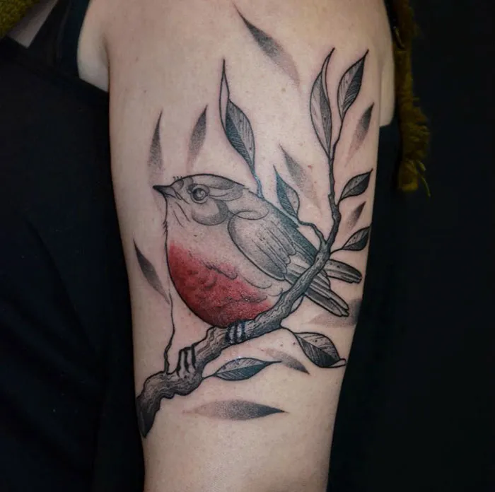 A colorful small bird tattoo with red and gray hues on a branch, showcasing elegant design.