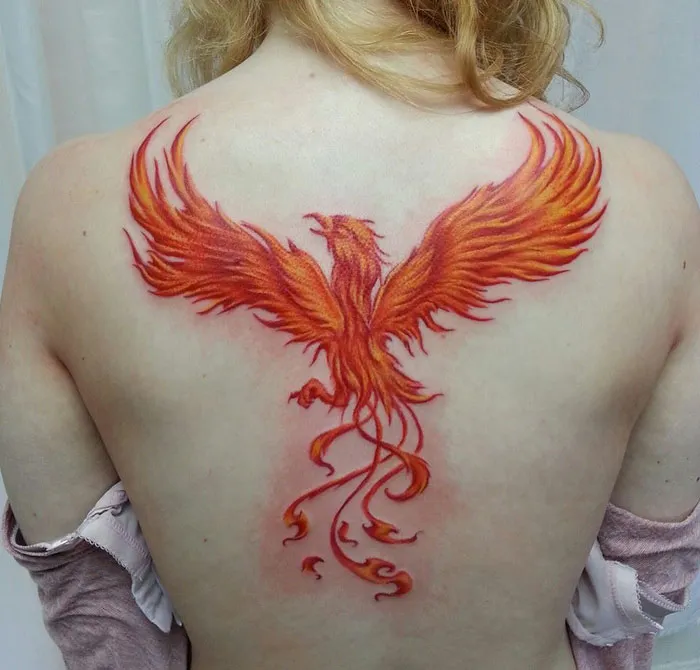 Vibrant phoenix tattoo on a person's back, showcasing unique small bird art.