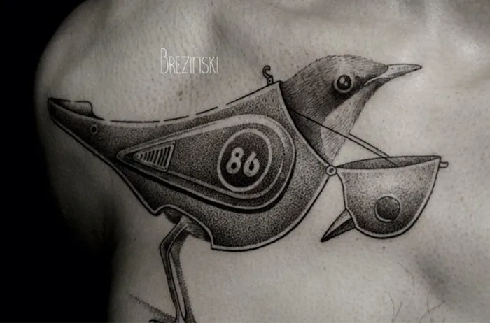Unique small bird tattoo design with mechanical elements and detailing on skin.