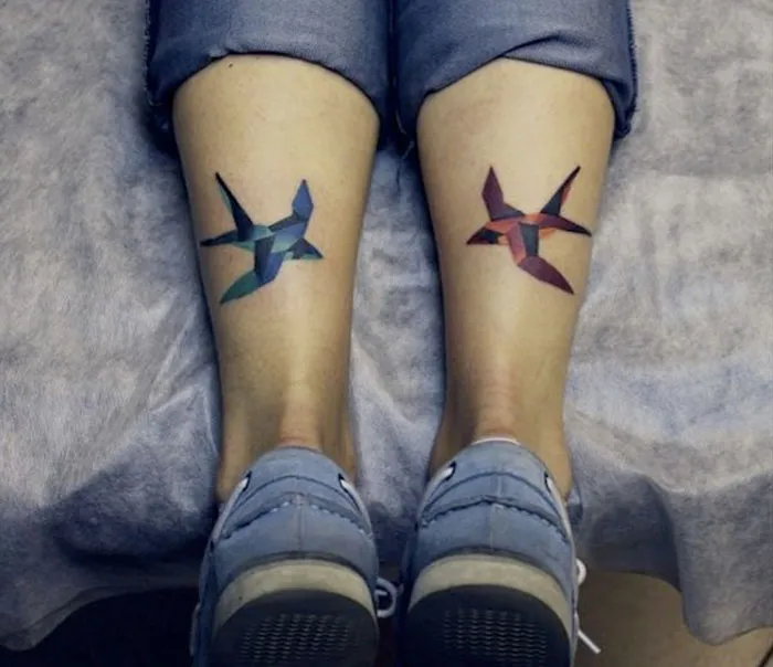 Abstract small bird tattoos in geometric style on legs.
