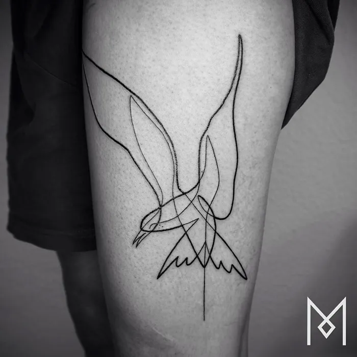 Line art small bird tattoo on thigh, showcasing minimalist design.