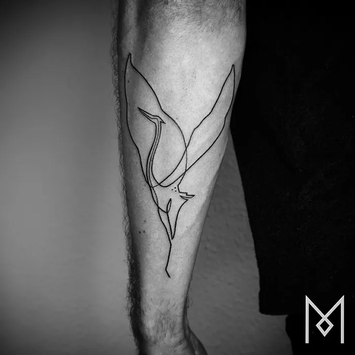 Minimalist line art small bird tattoo on forearm, showcasing unique tattoo design inspiration.