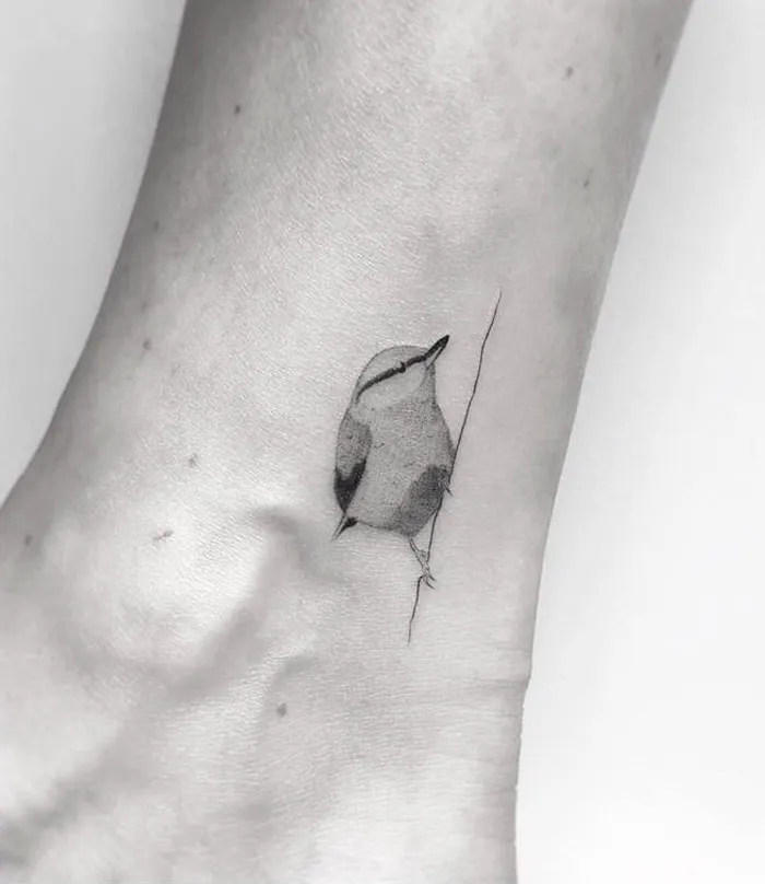 Small bird tattoo on ankle, minimalist ink design for inspiration.