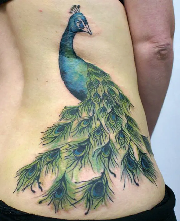 Peacock tattoo on back showcasing unique small bird design with vibrant blue and green feathers.