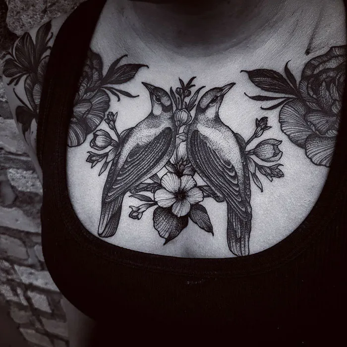 Small bird tattoo design on chest featuring two birds and floral elements.