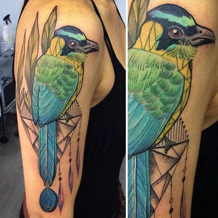 Colorful small bird tattoo with geometric accents on upper arm.