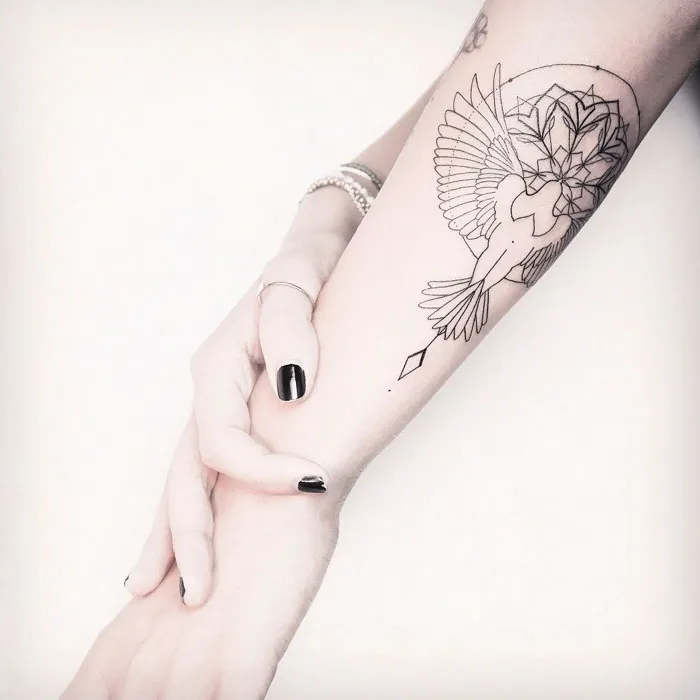 Unique small bird tattoo on forearm, featuring intricate geometric designs.