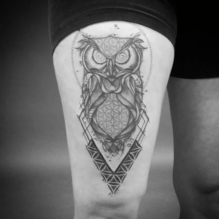 Geometric small bird tattoo design on a person's thigh, featuring intricate owl patterns.