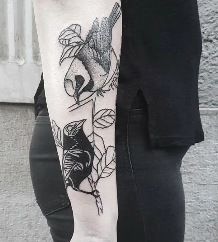 Small bird tattoos on forearm showcasing artistic black ink designs.