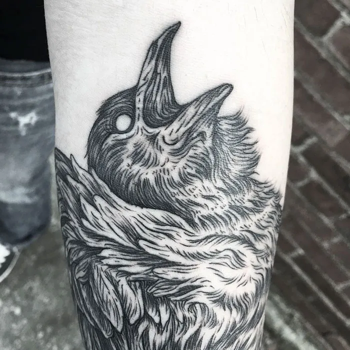 Detailed small bird tattoo design on forearm, showcasing intricate feather patterns.