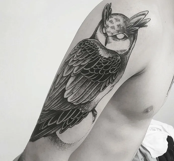 Unique small bird tattoo of an owl on a person's arm, showcasing intricate detail and shading.