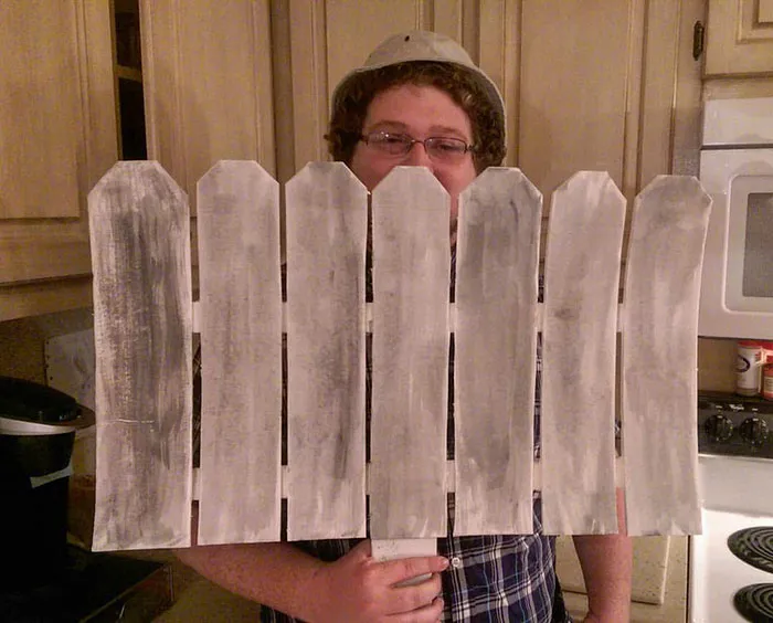 Man wearing a bucket hat hiding behind a cutout fence as creative Halloween costume ideas