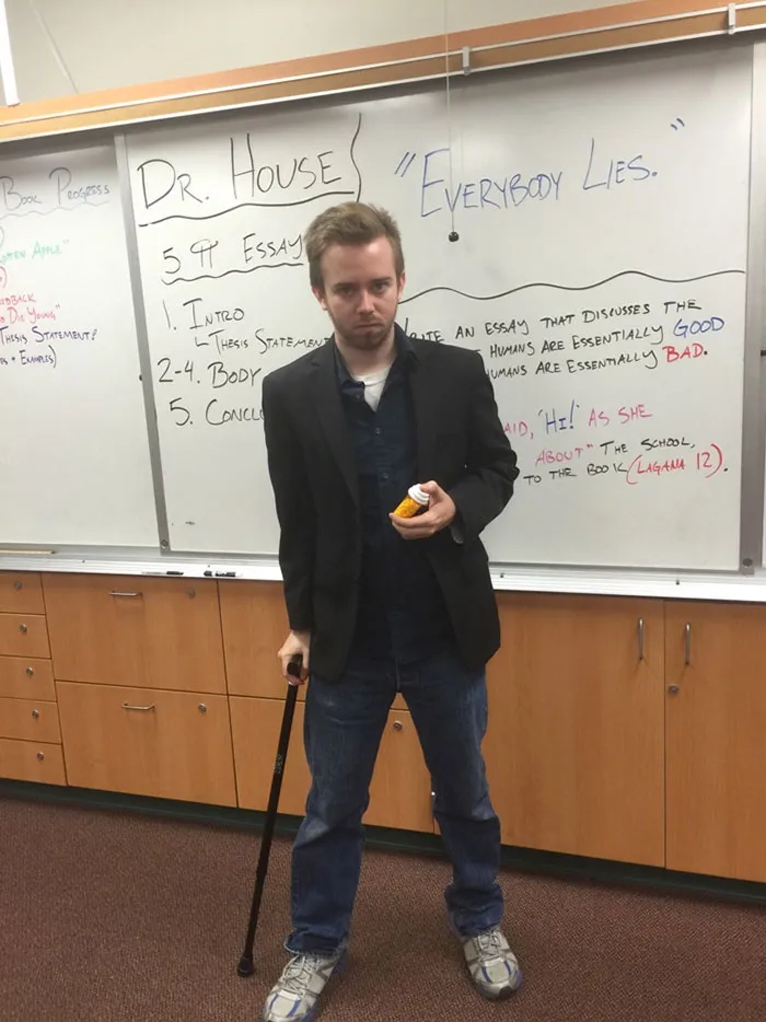 A man dressed as Dr. House in a creative Halloween costume holding a walking cane and pill bottle.