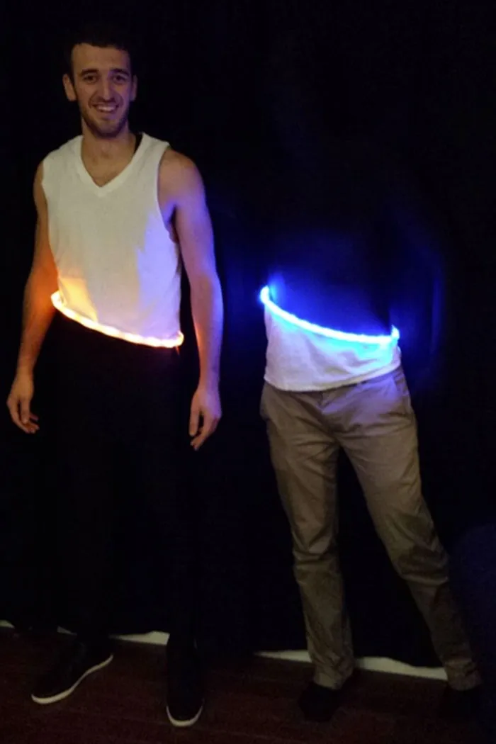 A man wearing glowing orange and blue rings creating a portal optical illusion, a creative Halloween costume idea.