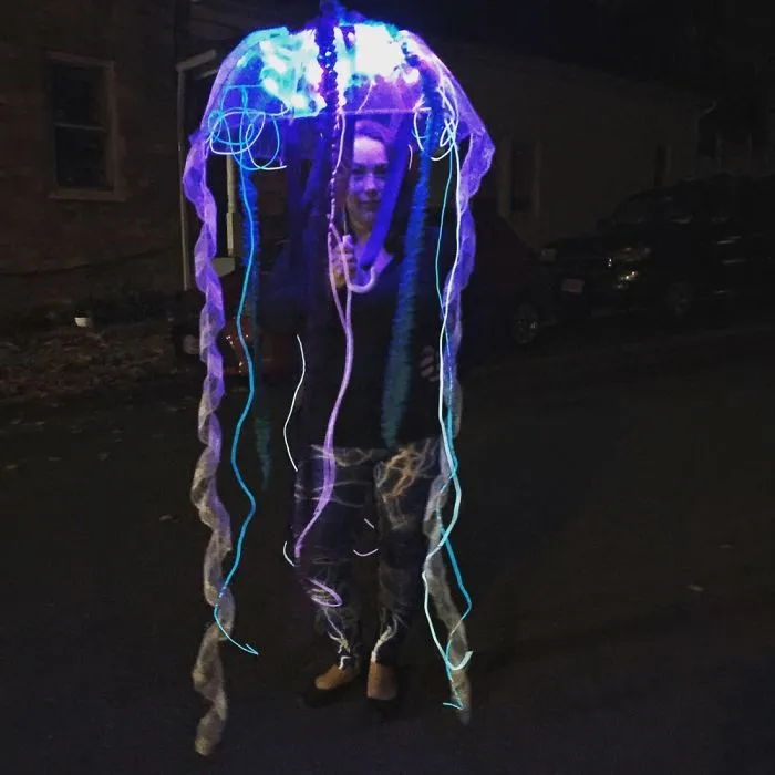 A glowing jellyfish umbrella creative Halloween costume worn by a woman at night