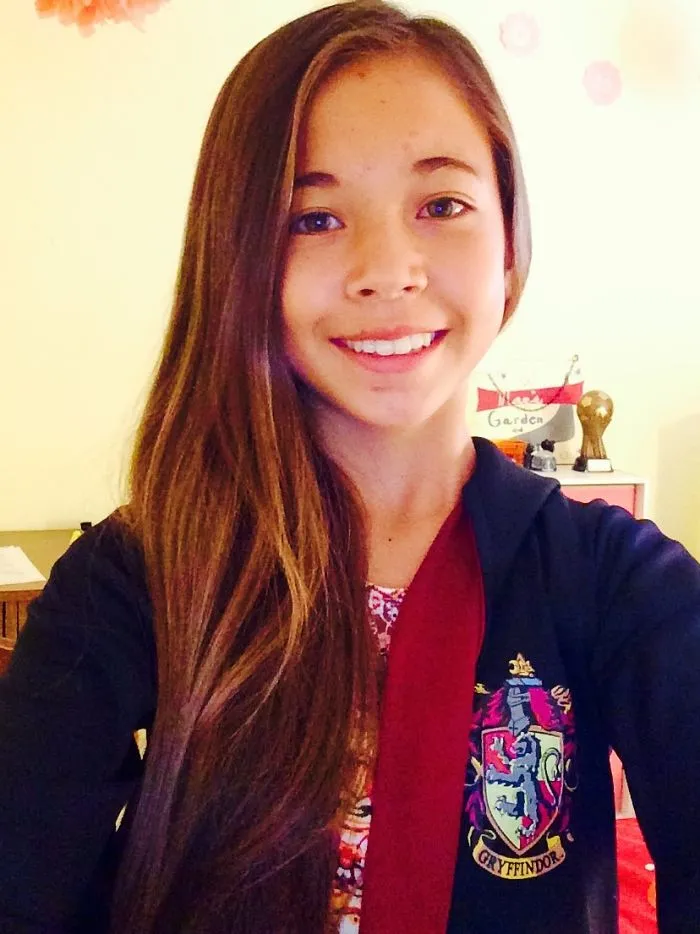 A smiling young girl wearing a Hogwarts crest hoodie presenting creative Halloween costume ideas