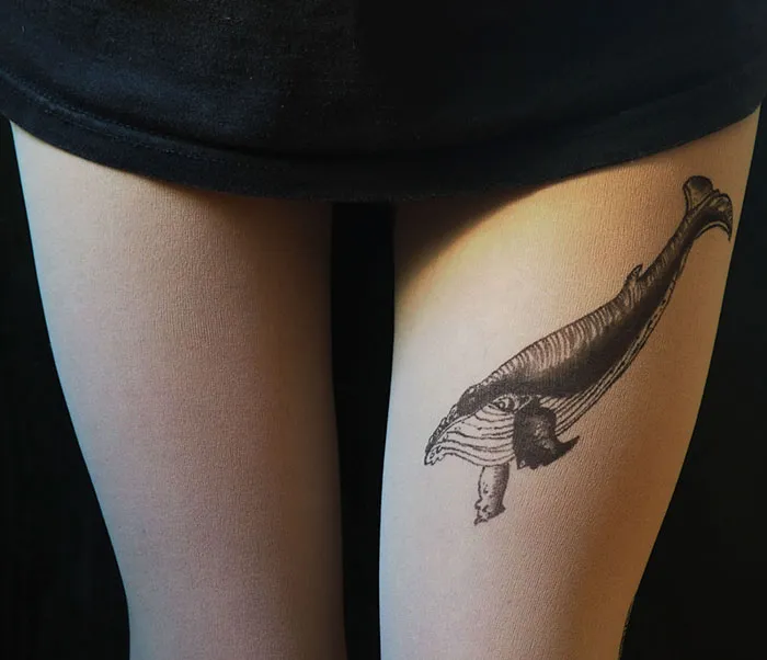 Tattoo tights with a whale design, creating an inked illusion on legs, worn with a black skirt.