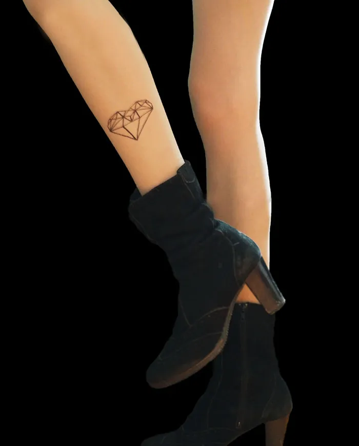 Legs with tattoo tights showing a heart design illusion, paired with black boots.
