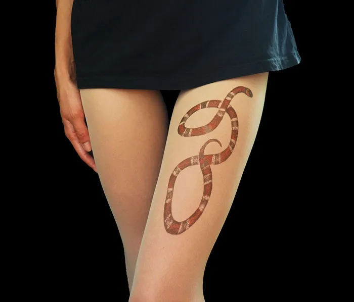 Tattoo tights featuring a snake design create an illusion of inked legs under a black skirt.