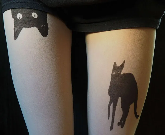 Tattoo tights featuring black cat designs creating an inked illusion on legs.