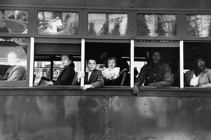 People of diverse backgrounds sitting inside a historic bus, looking out from the windows, capturing an iconic moment.