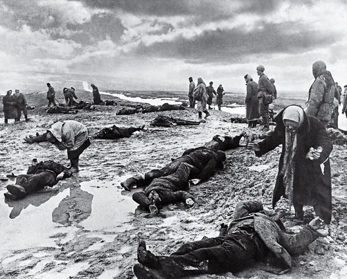 Historical photo showing people standing and lying on a battlefield, reflecting the somber aftermath of conflict.
