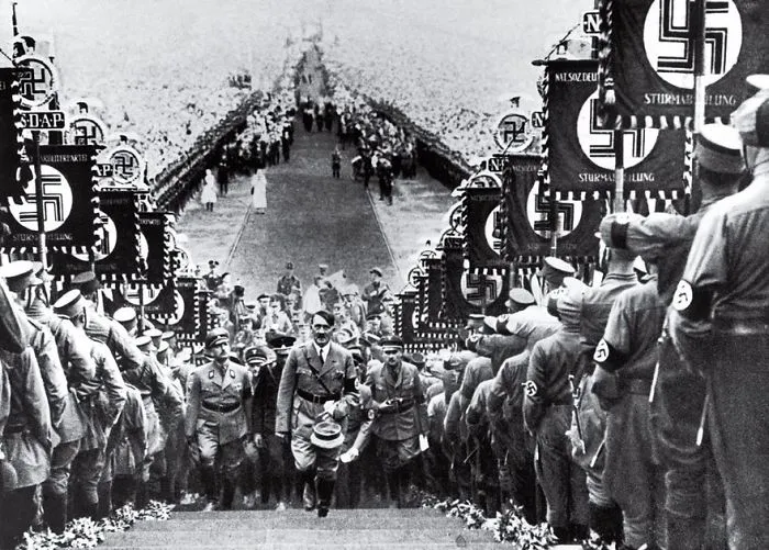 A historical photo showing a large group of men in uniform with Nazi symbols during a notable event in history.