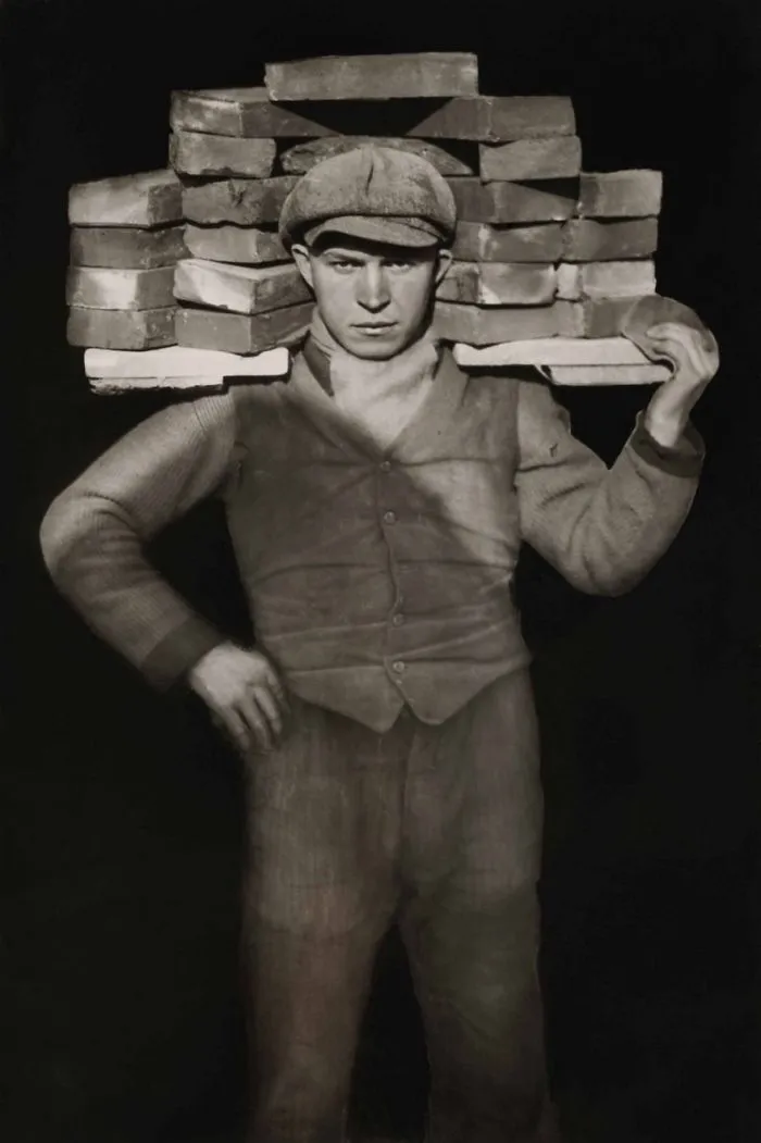 Man carrying bricks on shoulders, iconic historical photograph.