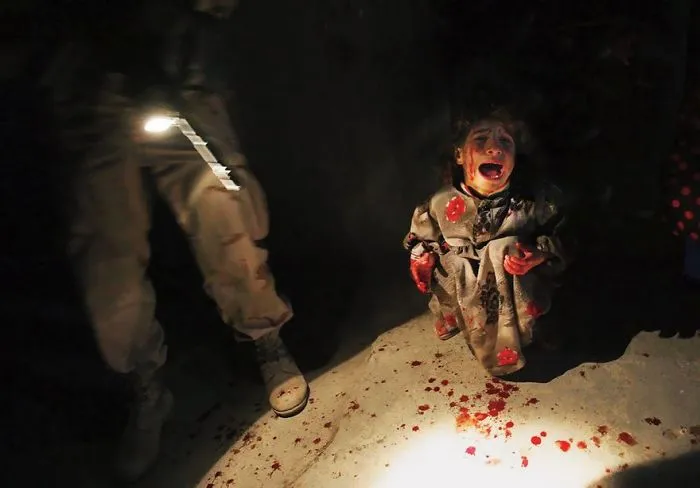A child crying on a blood-stained floor next to a soldier, depicting a powerful historical photo.