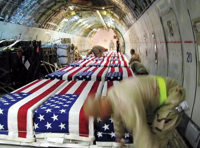 Soldiers organizing American flag-draped coffins inside an aircraft, symbolizing sacrifice in a famous historical photo.