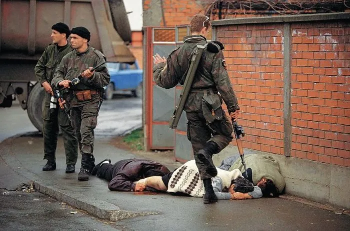 Soldiers in military gear walk past two civilians lying on the ground, showcasing a famous historical moment.