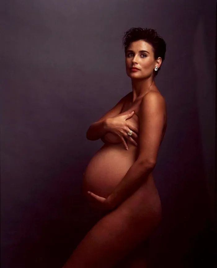 Pregnant woman posing in an iconic photograph with a dark backdrop.